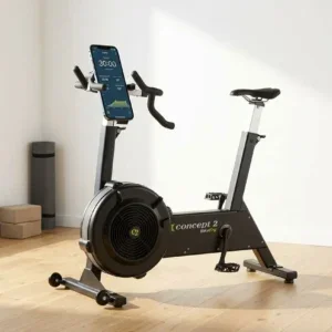 velo-dappartement-concept2-bikeerg-espace-fitness-maison Vélo d'appartement Concept2 BikeErg dans un espace fitness maison avec parquet clair et smartphone monté sur le guidon.
